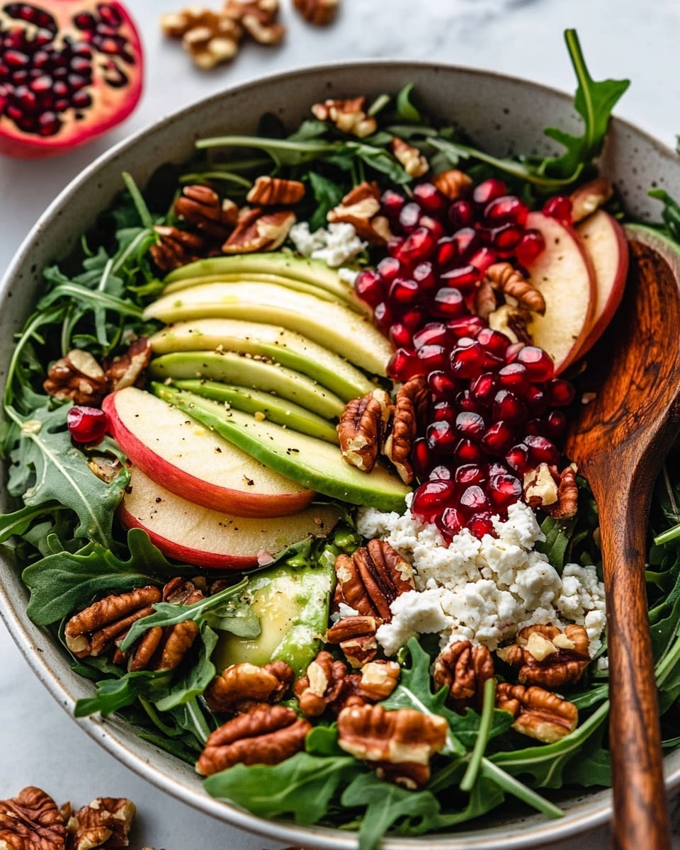 Two white bowls full of fresh green arugula leaves mixed with light red-tan apple slices, dark brown candied pecans, and small red pomegranate seeds, sitting on a rough wooden surface, with some pecans and pomegranate seeds scattered around. The salad looks glossy and fresh with a few green avocado pieces mixed in. Photo taken with an iphone --ar 4:5 --v 6.1