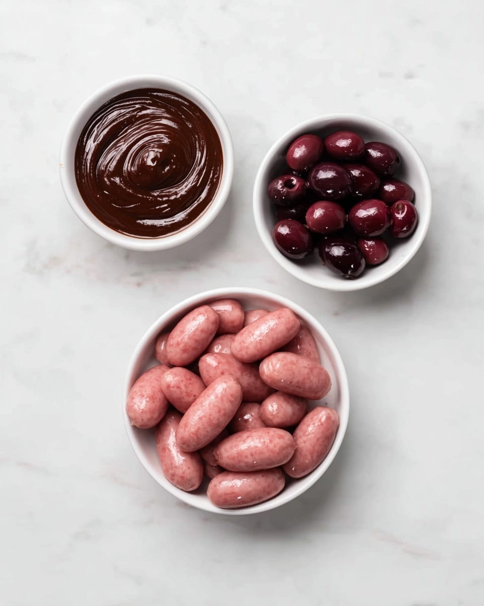 The image shows three white dishes on a white marbled surface. The largest dish is a white rectangular plate filled with many small light pink raw sausages, stacked closely together. To the top right of this plate, there is a small white round bowl filled with shiny dark purple cherries. To the left of the cherries, there is another small white round bowl holding a rich, dark brown sauce with a smooth, swirled texture on its surface. The overall scene is clean and simple, with a clear focus on the ingredients. photo taken with an iphone --ar 4:5 --v 7