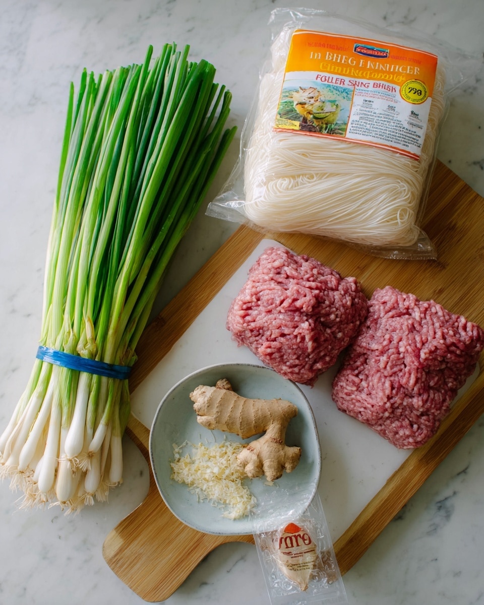 The image shows a bundle of fresh green onions with white tips on the left, a large orange and white package of rice noodle sticks standing upright in the center, a tan bowl containing a mound of raw ground meat on the top right, a whole piece of fresh ginger root just below the bowl, and a clear plastic bag filled with crushed yellowish ginger or garlic placed underneath and slightly behind the ginger root. All items rest on a white marbled surface. Photo taken with an iphone --ar 4:5 --v 7