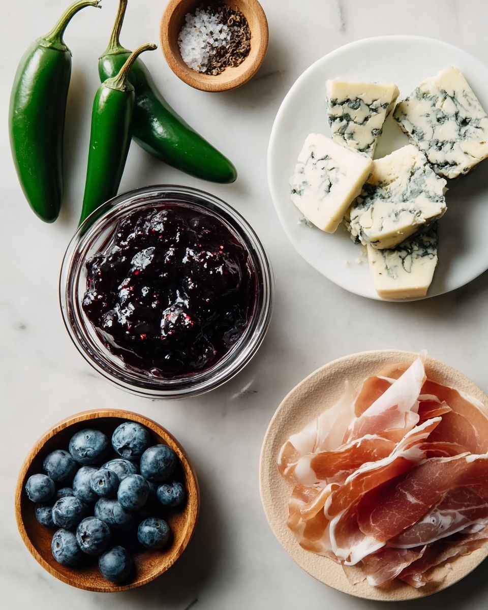 The image shows a small white marbled board placed on a white marbled surface with a small pile of torn thin slices of pink and white cured meat on the bottom right. Above it, there are uneven chunks of blue-veined cheese with a creamy white and blue marbled color. In the center, there is a small clear glass bowl filled with dark purple berry jam with a glossy texture. On the left, three whole green jalapeño peppers with smooth skins lie side by side. Below the peppers, a small round wooden bowl holds a handful of fresh blueberries with a powdery blue surface. Above the jalapeños, another small round wooden bowl contains coarse salt mixed with black pepper. Photo taken with an iphone --ar 4:5 --v 7